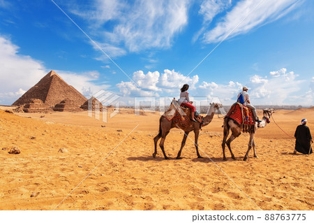 Tourists, camels, bedouins and the Pyramids in Giza desert Tourists, camels, bedouins and the Pyramids in Giza desert 88763775