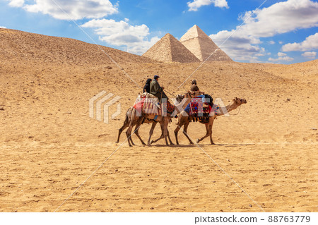 Egyptian men on camels in the sands of Giza near the Pyramids Egyptian men on camels in the sands of Giza near the Pyramids 88763779