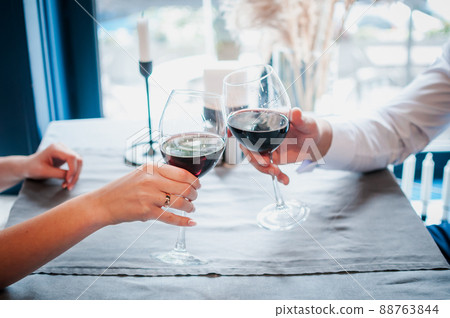 Two people clinking glasses with red wine 88763844