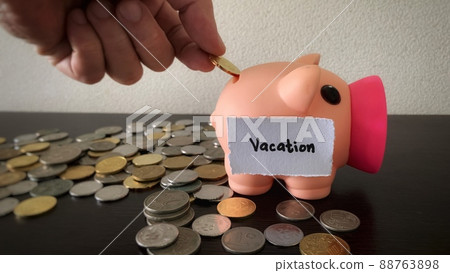 Hand putting coin to piggy bank for vacation. Money concept Hand putting coin to piggy bank for vacation. Money concept 88763898