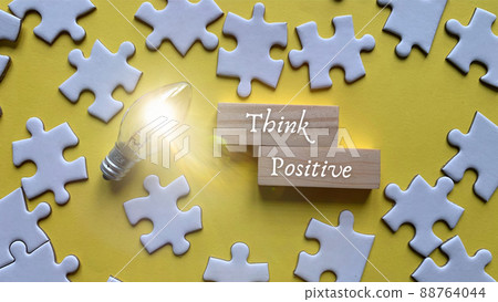 Top view of words - Think positive. With jigsaw puzzle and bulb background. 88764044