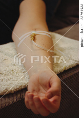 Woman's hand with catheter for dropper, butterfly needle used to draw blood from a vein or to deliver intravenous therapy to vein. Thin needle, flexible transparent tubing. Patient in nmedical clinic. Woman's hand with catheter for dropper, butterfly needle used to draw blood from a vein or to deliver intravenous therapy to vein. Thin needle, flexible transparent tubing. Patient in nmedical clinic. 88764588