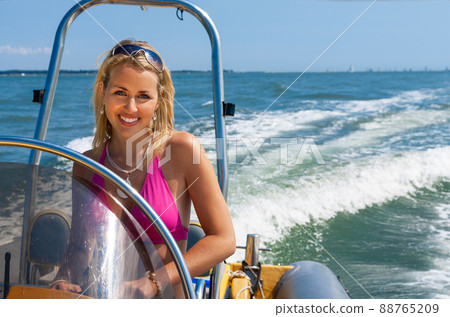 Beautiful Girl Young Woman in Bikini Driving Speed Boat on a Blue Sea Beautiful Girl Young Woman in Bikini Driving Speed Boat on a Blue Sea 88765209