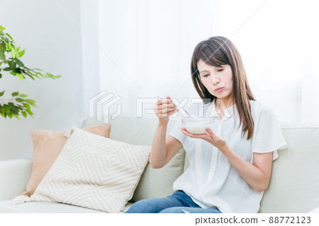 A woman eating yogurt on the sofa (problem) A woman eating yogurt on the sofa (problem) 88772123