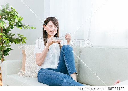 一個女人在沙發上吃酸奶(微笑) 一個女人在沙發上吃酸奶(微笑) 88773151