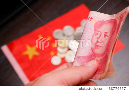 RMB banknotes of Chinese yuan money on the hand with a coins and China flag blurred on background 88774857