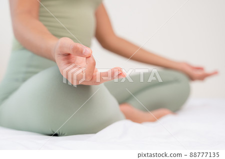 Woman practicing meditation on the bed. Doing yoga breathing with Ardha Padmasana exercise. Woman practicing meditation on the bed. Doing yoga breathing with Ardha Padmasana exercise. 88777135