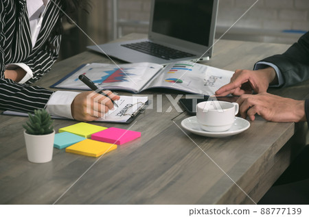 Businesswoman signing business contract while businessman using tablet at office. Businesswoman signing business contract while businessman using tablet at office. 88777139