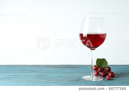 Glass of red wine and grape on wooden table Glass of red wine and grape on wooden table 88777388