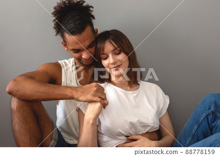 guy and girl sit at home on the floor against a gray wall guy and girl sit at home on the floor against a gray wall 88778159