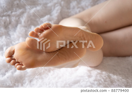 Women's feet close-up. A woman lies on her stomach, morning, the rays of the sun. Women's feet close-up. A woman lies on her stomach, morning, the rays of the sun. 88779400