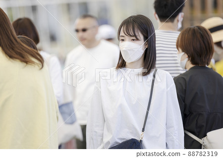 A woman wearing a mask and walking in a crowd A woman wearing a mask and walking in a crowd 88782319