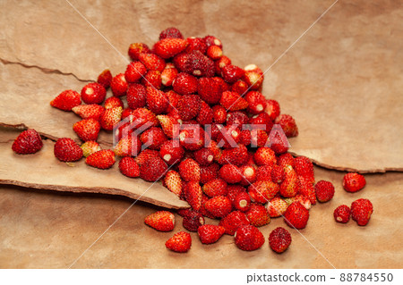 Red wild strawberry on brown wooden background 88784550