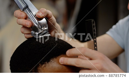 The trimmer cuts the curled hair of an African American - macro shot The trimmer cuts the curled hair of an African American - macro shot 88785774