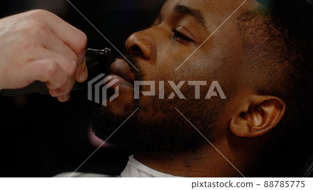 A white-skinned guy straightens the line of his mustache to a young African-American guy A white-skinned guy straightens the line of his mustache to a young African-American guy 88785775