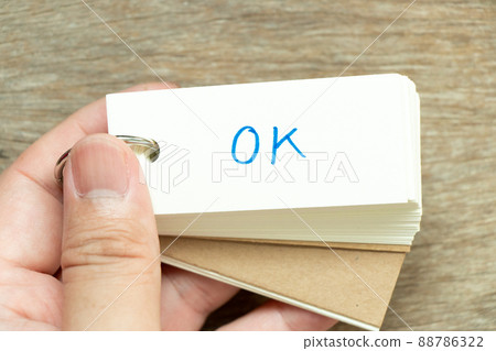Man hold the flash card with handwriting word OK on wood background 88786322
