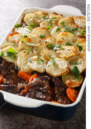 Lancashire Hotpot Succulent lamb in a meaty gravy, topped with potatoes that are tender underneath and crisp on top closeup in the baking dish. Vertical Lancashire Hotpot Succulent lamb in a meaty gravy, topped with potatoes that are tender underneath and crisp on top closeup in the baking dish. Vertical 88787204