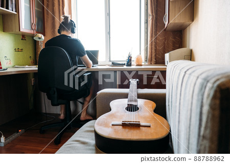 Guitar lessons for beginners. Close up of guitar and teenager boy at home. Online Guitar Lessons, enjoying favorite hobby, leisure. Acoustic guitars for beginners. 88788962