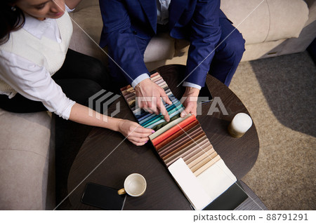 Focus on samples of colored fabrics for upholstered furniture. Top view of couple choosing color and fabric texture for upholstery sofa in the home. Interior design concept Focus on samples of colored fabrics for upholstered furniture. Top view of couple choosing color and fabric texture for upholstery sofa in the home. Interior design concept 88791291