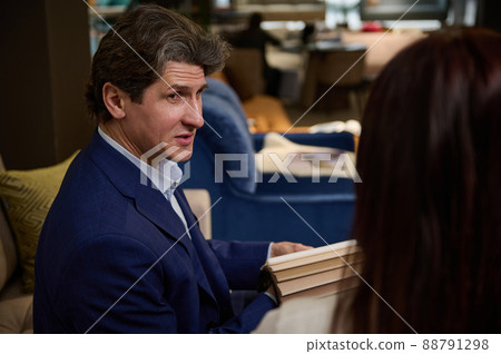 Handsome sales representative in a furniture store presents to the buyer samples of colored fabrics for upholstery of a sofa 88791298