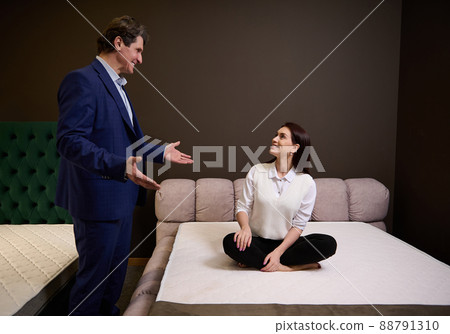 Furniture store sales manager helping a beautiful woman client buyer to choose an orthopedic mattress for good posture and healthy sleep Furniture store sales manager helping a beautiful woman client buyer to choose an orthopedic mattress for good posture and healthy sleep 88791310