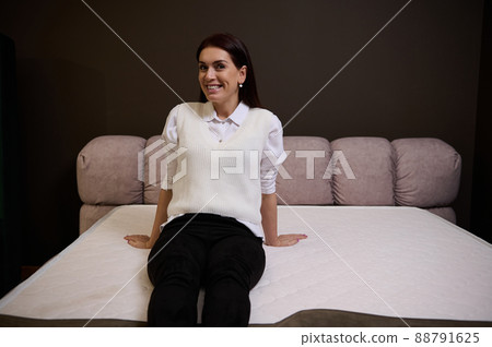 Beautiful woman choosing an orthopedic mattress in the furniture store showroom Beautiful woman choosing an orthopedic mattress in the furniture store showroom 88791625
