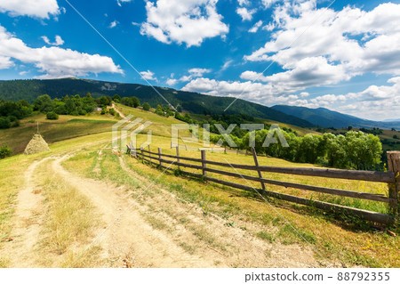 rural road through grassy meadows. wonderful countryside landscape with rolling hills beneath a gorgeous sky with clouds on a summer evening rural road through grassy meadows. wonderful countryside landscape with rolling hills beneath a gorgeous sky with clouds on a summer evening 88792355