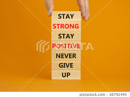 Never give up symbol. Wooden blocks with concept words Stay strong stay positive never give up. Beautiful orange background. Copy space. Businessman hand. Motivational business never give up concept. 88792495