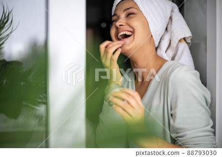 Happy domestic woman applying anti aging cream from jar on face looking at mirror 88793030