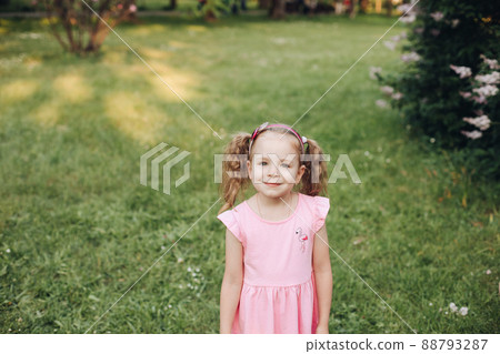 A little cute baby girl in a pink dress in a green 88793287