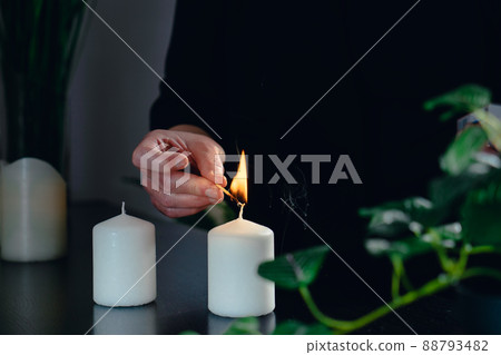 Close-up of the hands of a female beautician lighting scented candles in her small spa business. 88793482