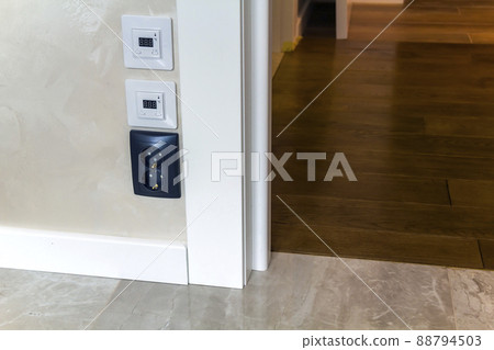 Modern house interior with warm floor controller panels on the wall, wooden parquet and white door 88794503