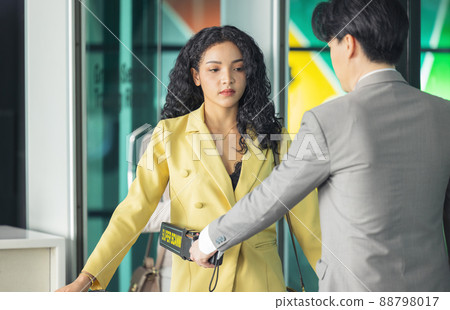 In the airport, people are going through the physical screening and luggage scanning procedures. 88798017