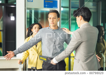 In the airport, people are going through the physical screening and luggage scanning procedures. 88798020