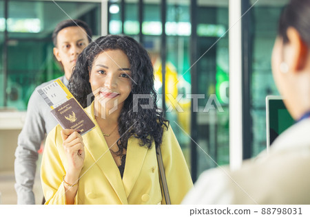 At the airport check-in counter, a passenger hands over his documents to the manager via a counter ticket. 88798031