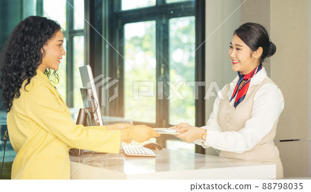 At the airport check-in counter, a passenger hands over his documents to the manager via a counter ticket. 88798035