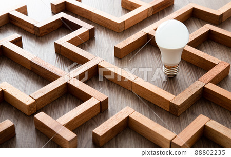 Light bulb in the maze game built by wood blocks, finding the right way to the success, idea concept 88802235
