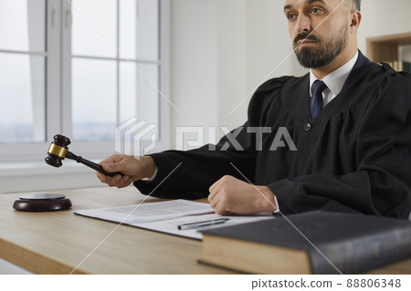 Fair serious male judge passes sentence and decides to close case during court hearing. Fair serious male judge passes sentence and decides to close case during court hearing. 88806348
