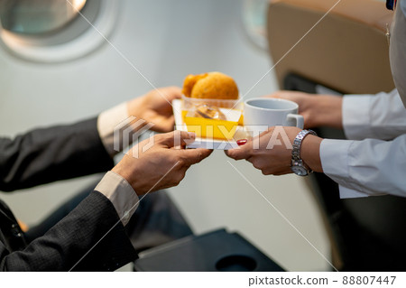 Close-up hands of passenger receive dessert and cake from air hostess or cabin crew during fly Close-up hands of passenger receive dessert and cake from air hostess or cabin crew during fly 88807447