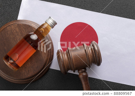 Wooden judge and bottle with alcohol on Japan flag background. Alcohol law in Japan. Wooden judge and bottle with alcohol on Japan flag background. Alcohol law in Japan. 88809567