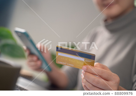 Close up shot of females hands holding credit card typing message on smart phone for shopping online 88809976