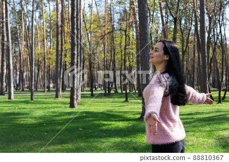 Woman walking in a park, smiling and enjoying fresh air. 88810367
