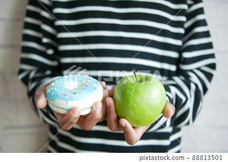 teenage boy hand holding donuts and apple  88813501