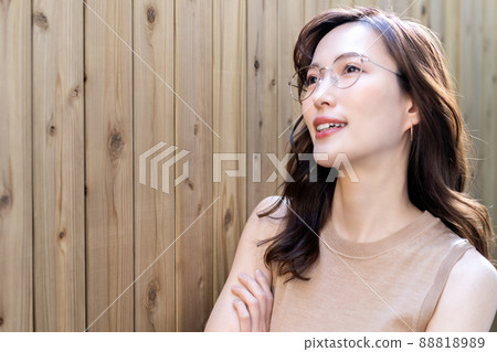 A woman with glasses smiling in front of a wood fence A woman with glasses smiling in front of a wood fence 88818989