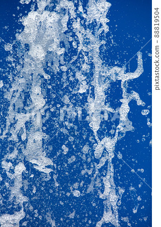 a jet of water sprayed under pressure from a fountain against a blue background frozen water movement close up abstract backdrop. 88819504
