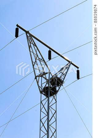 Two raven nests at the top of a power pole tower 88819874