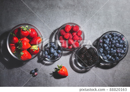 Assorted berries in glass bowls on dark background top view. Assorted berries in glass bowls on dark background top view. 88820163