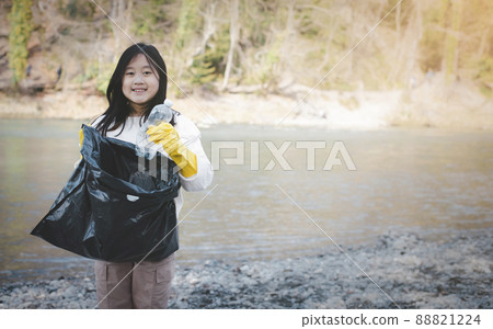 Earth Day concept, girl teens pick up garbage in litter bags, clean-ups in nature to recycling in their communities, clean river and protect the environment from pollution, conservation Nature. Earth Day concept, girl teens pick up garbage in litter bags, clean-ups in nature to recycling in their communities, clean river and protect the environment from pollution, conservation Nature. 88821224