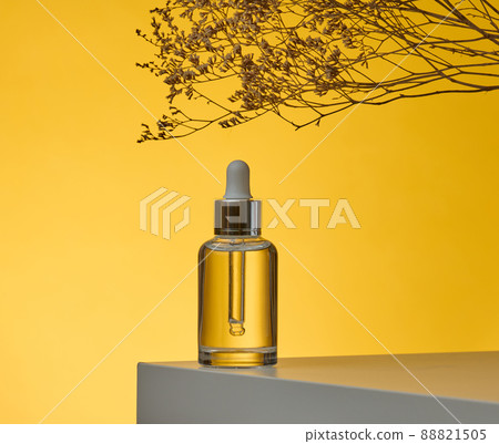 white glass transparent bottle with a pipette for cosmetics, oils, acids on a white table. yellow background white glass transparent bottle with a pipette for cosmetics, oils, acids on a white table. yellow background 88821505