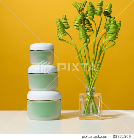 Green jar for cosmetics on a white table. Packaging for cream, gel, serum, advertising and product promotion Green jar for cosmetics on a white table. Packaging for cream, gel, serum, advertising and product promotion 88821509